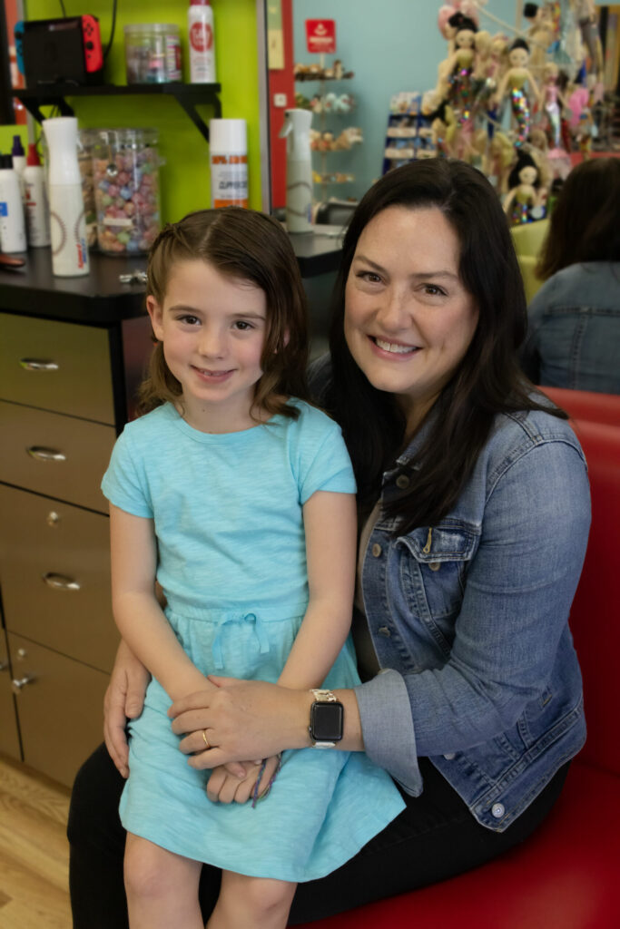 Little girl sitting on her mom's lap in the salon - Pigtails & Crewcuts Buckhead