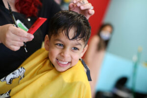 A smiling boy getting a fresh trim at Pigtails & Crewcuts Buckhead.