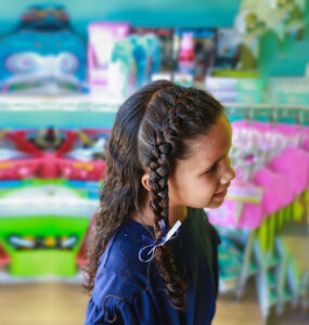 A girl with a sparkly side braid at Pigtails & Crewcuts Buckhead.