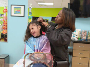 A little girl getting her hair braided at Pigtails & Crewcuts Buckhead: Haircuts for Kids.