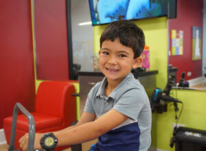 A smiling boy sitting in the styling chair, freshly groomed after his haircut at Pigtails & Crewcuts in Buckhead.