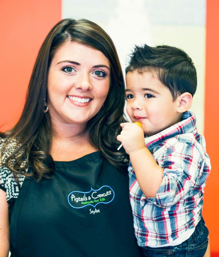 Pigtails & Crewcuts Hair Stylist holding a happy little boy