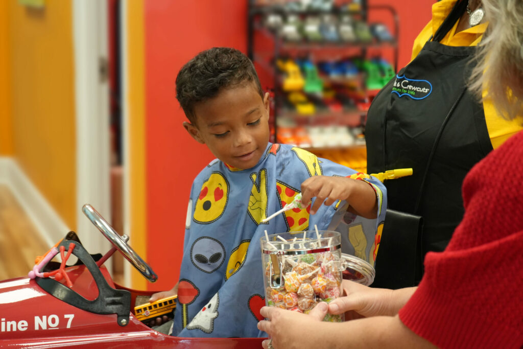 Little boy picking out a dum-dum lollipop - Pigtails & Crewcuts Smyrna