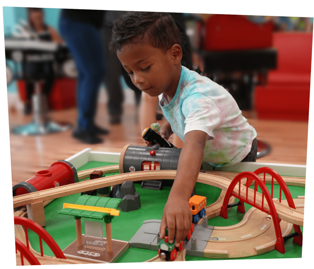 Boy playing at a train table at Pigtails & Crewcuts Greenville Augusta Road