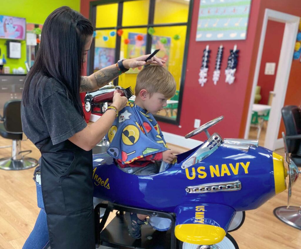 Boy getting his haircut in an airplane themed car at Pigtails & Crewcuts Greenville Five Forks
