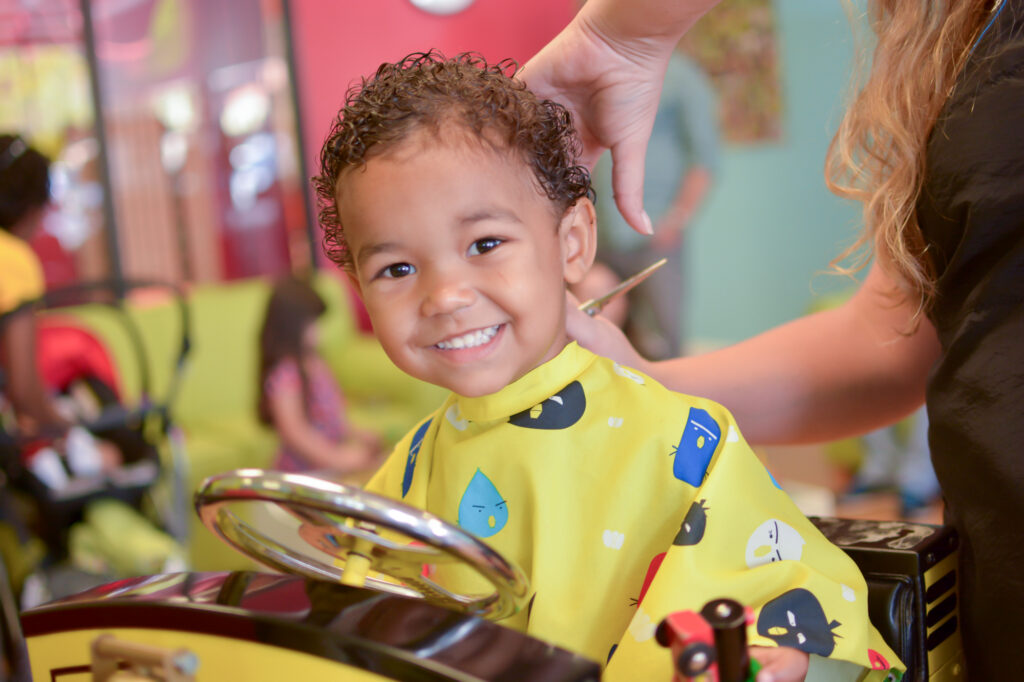 Smiling boy with curls getting a haircut - Pigtails & Crewcuts Jacksonville