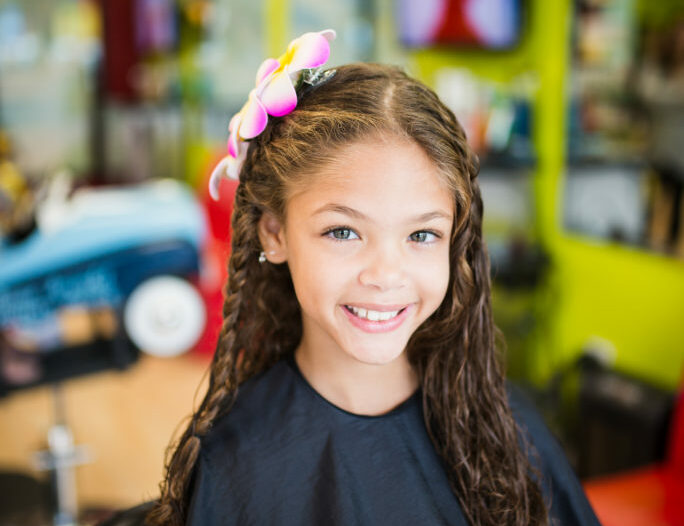 Smiling girl with flower in her hair - Pigtails & Crewcuts Jacksonville