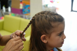 Girl getting her hair braided in the salon - Pigtails & Crewcuts Jacksonville