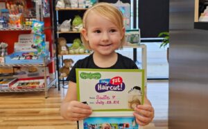 Little girl with her 1st Haircut Certificate after her first haircut at Pigtails & Crewcuts Roswell