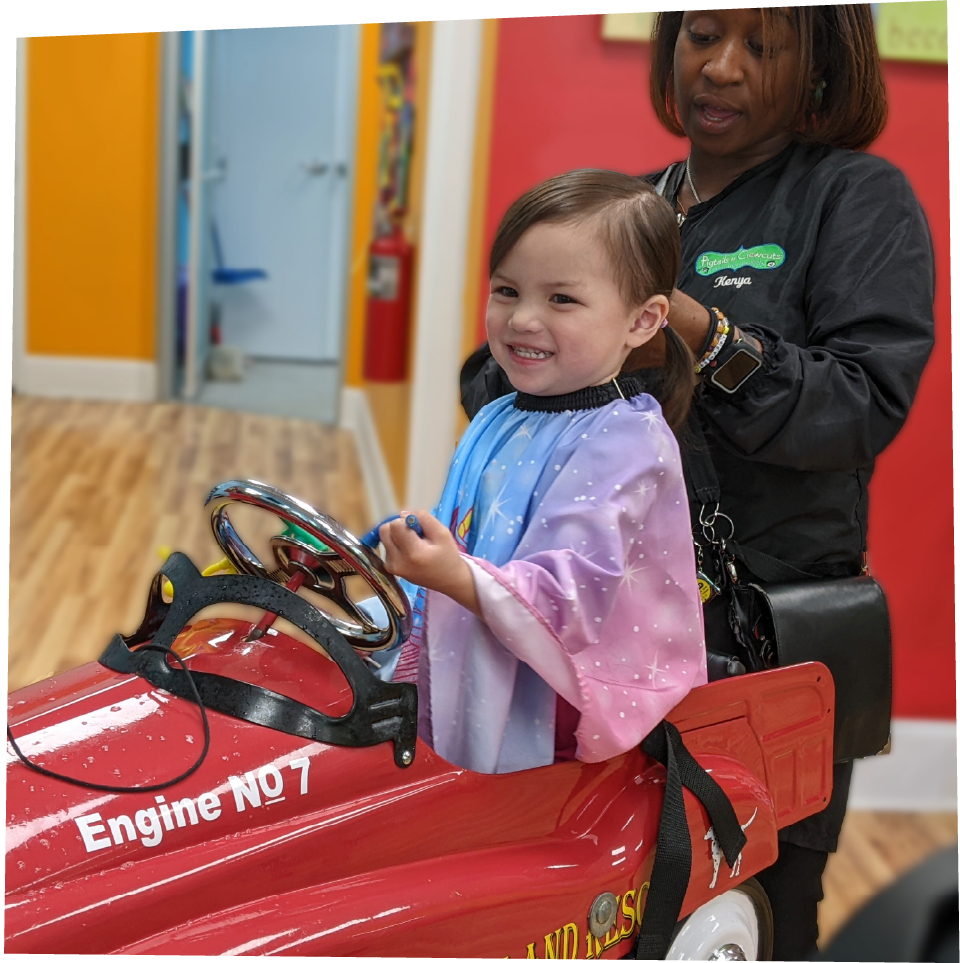 Happy Pigtails & Crewcuts stylist and excited little girl getting a haircut