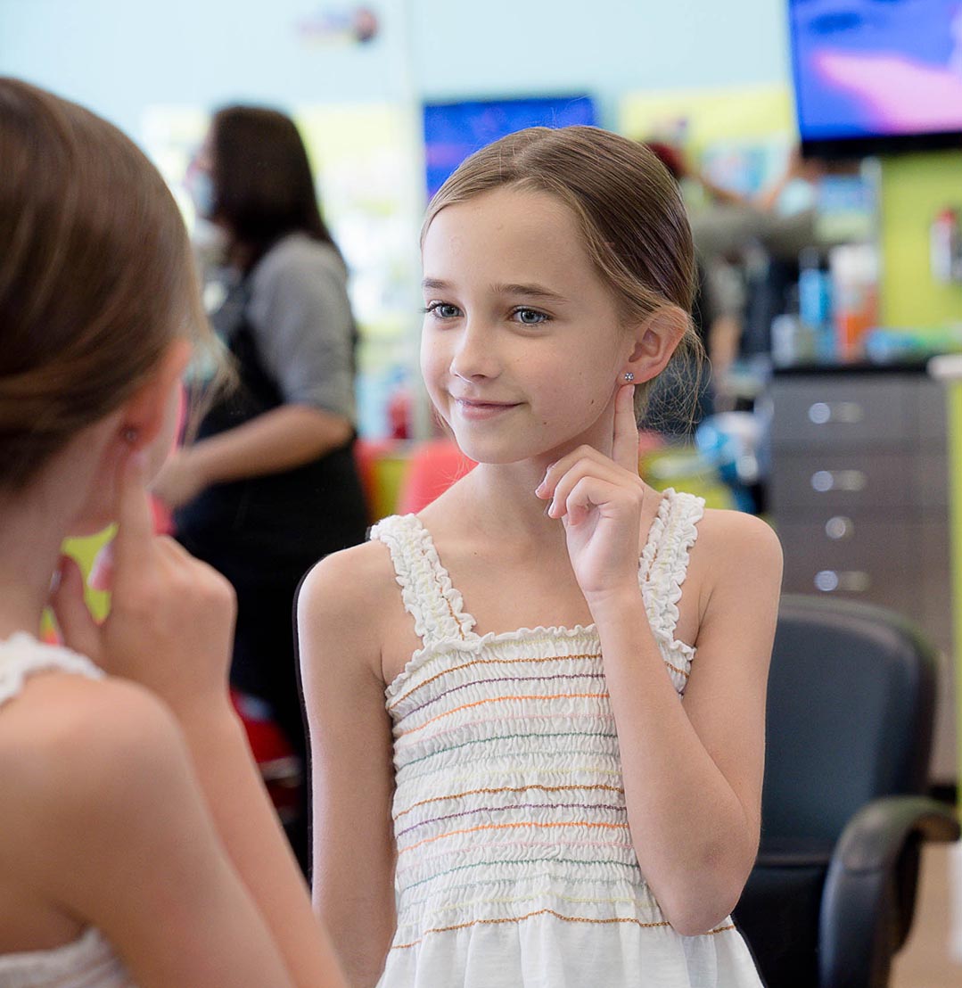 Girl happy with her ear piercing from Pigtails & Crewcuts Atlanta Buckhead