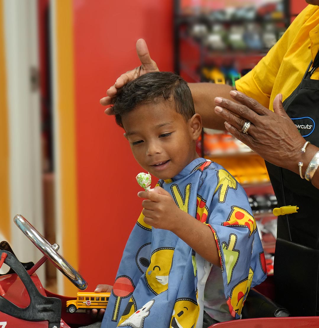 Happy boy getting a haircut and Dum Dum at Pigtails & Crewcuts Atlanta Buckhead