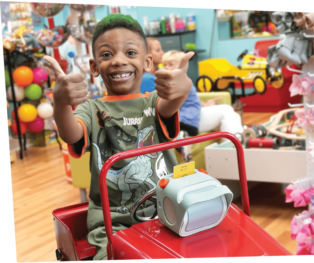 Smiling boy with his thumbs up and a Yoto player at Pigtails & Crewcuts